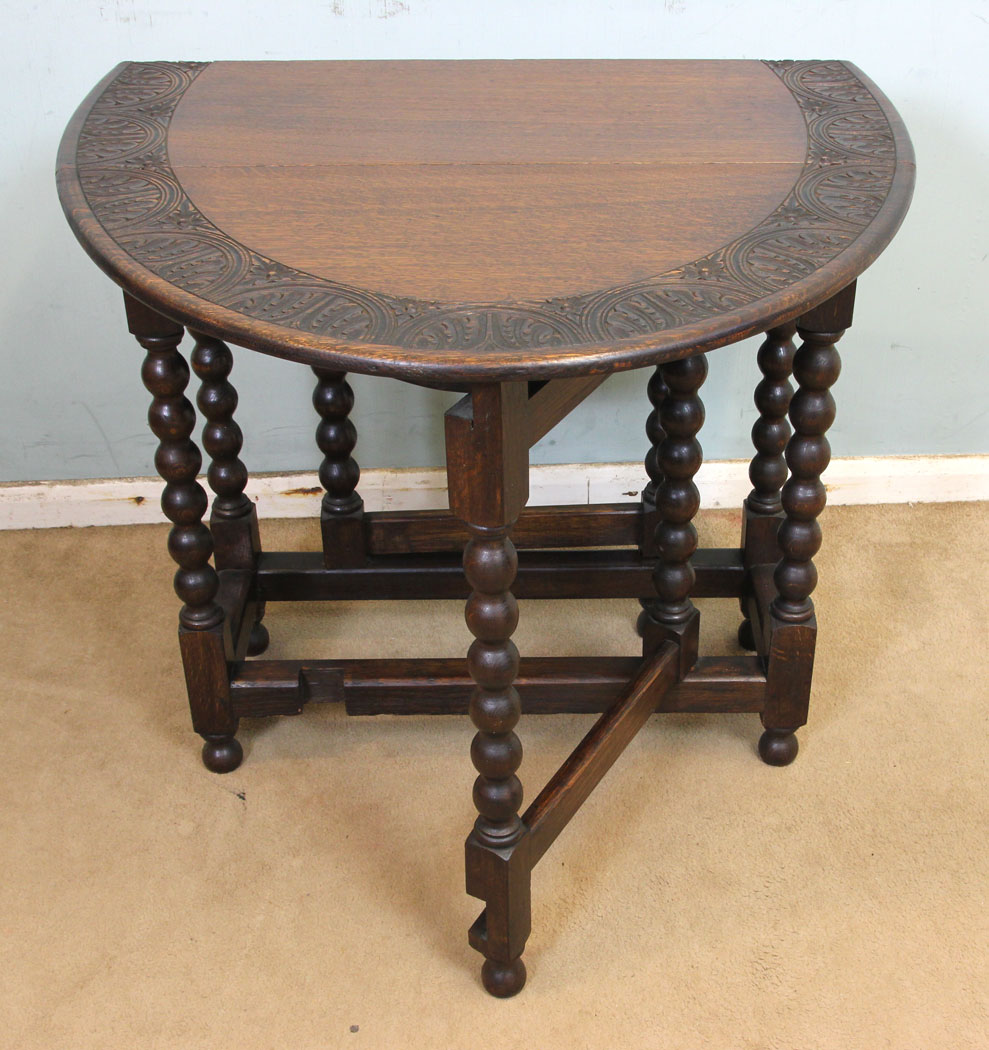 11247r2 Antique Drop Leaf Oak Gateleg Table, Antique Carved Solid Oak Gateleg Drop Leaf Occasional Table. This solid oak gateleg drop leaf occasional table has a oval top with carved edge detail and is supported by turned bobbin legs and stretchers.