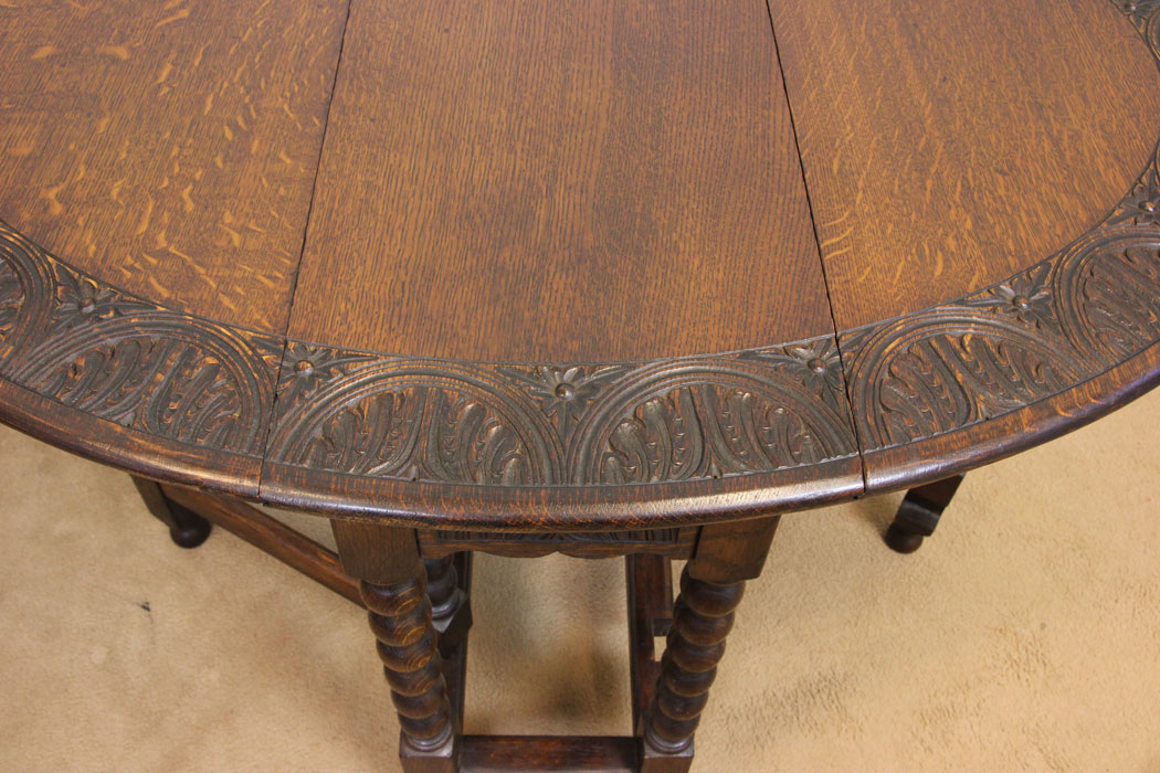 11247r4 Antique 20th Century Oak Gateleg Table, Antique Carved Solid Oak Gateleg Drop Leaf Occasional Table. This solid oak gateleg drop leaf occasional table has a oval top with carved edge detail and is supported by turned bobbin legs and stretchers.