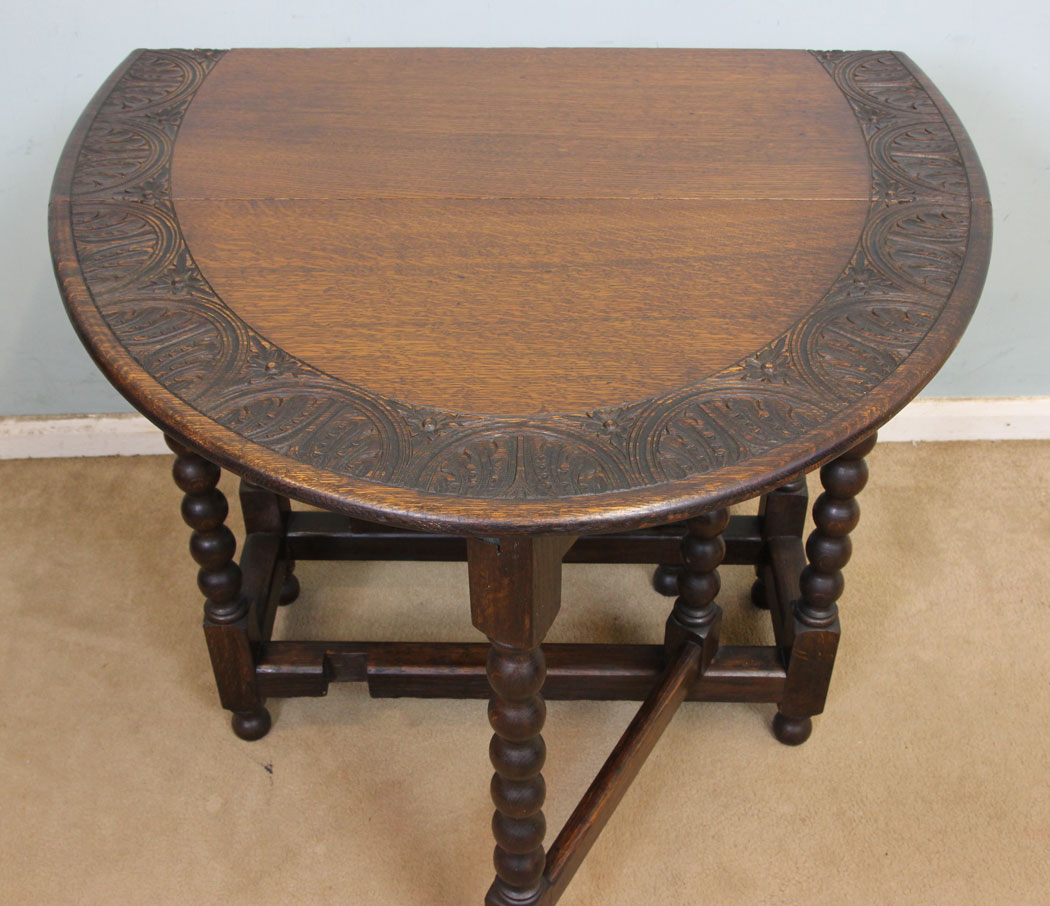11247r7 Antique Oak Gateleg Table, Antique Carved Solid Oak Gateleg Drop Leaf Occasional Table. This solid oak gateleg drop leaf occasional table has a oval top with carved edge detail and is supported by turned bobbin legs and stretchers.