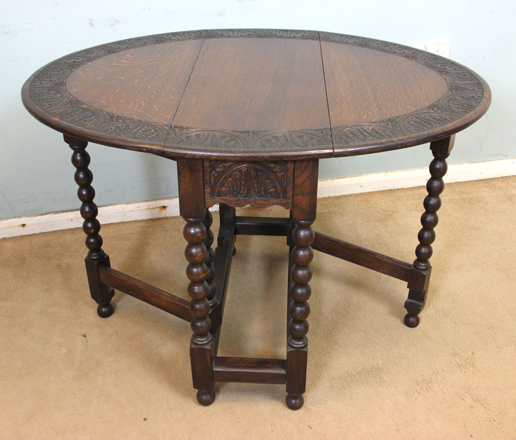 11247r8 Antique Carved Oak Gateleg Table, Antique Carved Solid Oak Gateleg Drop Leaf Occasional Table. This solid oak gateleg drop leaf occasional table has a oval top with carved edge detail and is supported by turned bobbin legs and stretchers.