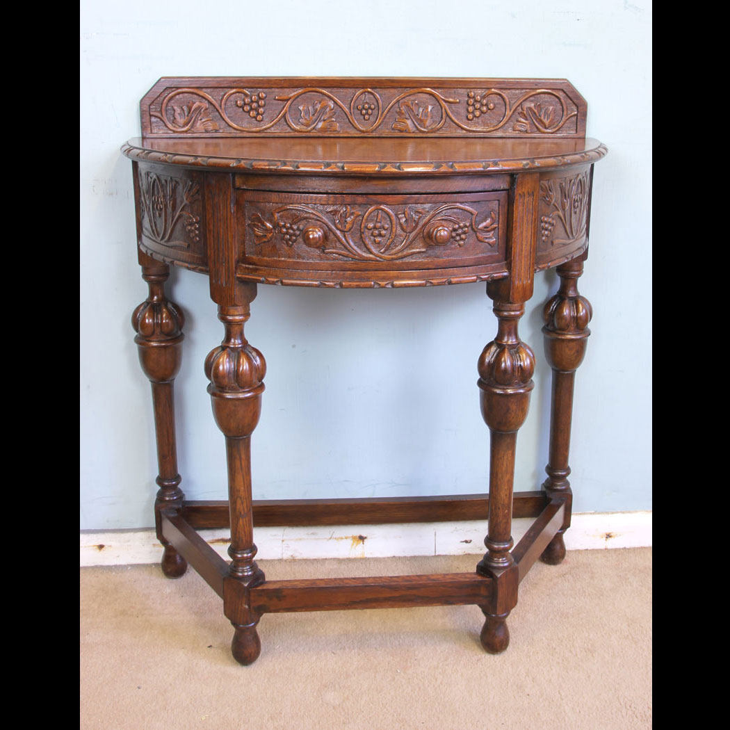 11375r01 Antique Jacobean Style Carved Oak Demi Lune Side Table Antique Jacobean Style Carved Oak Demi Lune Side Table. This lovely carved oak demi lune / side table has a low carved upstand to the back and carved detail to the top edge