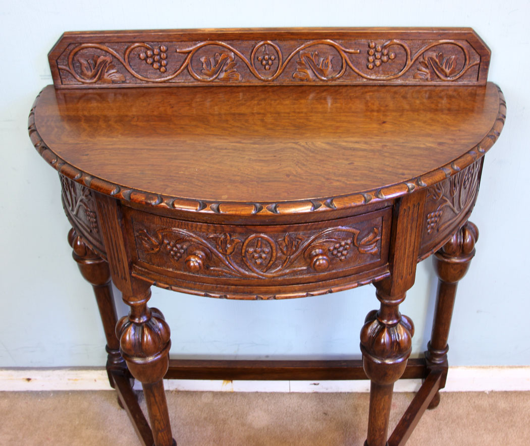 11375r6 Antique Oak Side Table, Antique Jacobean Style Carved Oak Demi Lune Side Table. This lovely carved oak demi lune / side table has a low carved upstand to the back and carved detail to the top edge