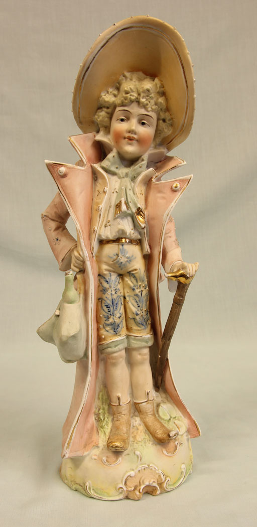 11384r1 Antique Bisque Figurine of Gentleman, Antique Bisque Figurine of Gentleman. This lovely bisque figure of young gentleman is dressed in period clothing and hat all in lovely colours and having hand painted detail with gilt decoration he is holding a bag and a cane. There is a slight chip on the bag see photo. Circa 1900