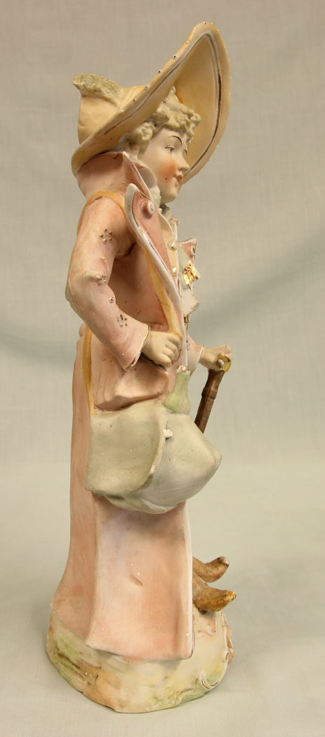 11384r3 Antique Bisque Figurine of Gentleman, Antique Bisque Figurine of Gentleman. This lovely bisque figure of young gentleman is dressed in period clothing and hat all in lovely colours and having hand painted detail with gilt decoration he is holding a bag and a cane. There is a slight chip on the bag see photo. Circa 1900