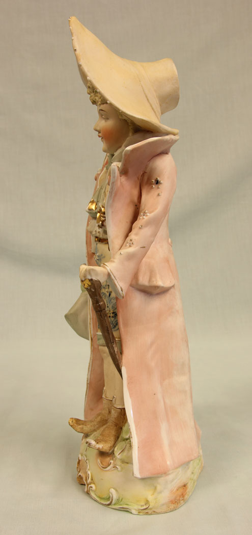 11384r4 Antique Bisque Figurine of Gentleman, Antique Bisque Figurine of Gentleman. This lovely bisque figure of young gentleman is dressed in period clothing and hat all in lovely colours and having hand painted detail with gilt decoration he is holding a bag and a cane. There is a slight chip on the bag see photo. Circa 1900
